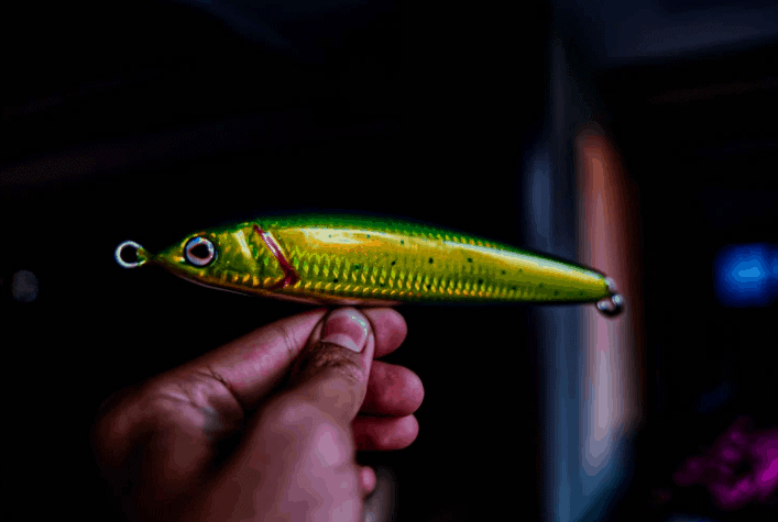 Hand holding golden-colored fish bait